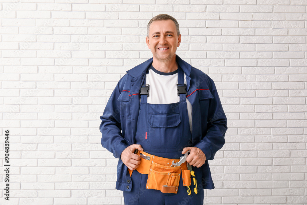 Sticker portrait of male mechanic with tool belt on white brick background