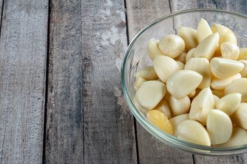 half of a glass bowl filled garlic on wooden table