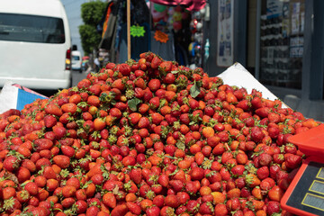 Pile of juicy and ripe strawberries at an outdoor market, ready for sale in a fresh fruit retail store that is selling them outdoors by a small business