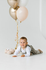 Smiling happy birthday baby crawling on the floor against the background of balloons