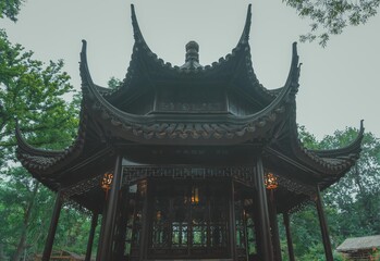An intricately detailed, dark wooden gazebo sits amidst lush greenery in a Chinese garden.