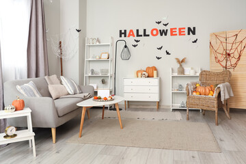 Interior of light living room decorated for Halloween with sofa and armchair
