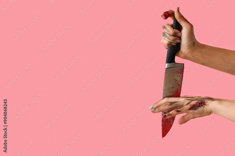 Wall mural Zombie hands with bloodstained knife on pink background. Halloween celebration