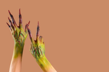 Hands of witch with claws on beige background. Halloween celebration