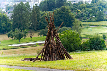 Tipi shaped tree trunks of bonfire ready for national holiday of Switzerland on meadow at Swiss City of Zürich on a summer morning. Photo taken August 1st, 2024, Zurich, Switzerland. © Michael Derrer Fuchs