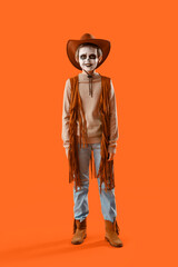 Little boy dressed for Halloween as cowboy on orange background