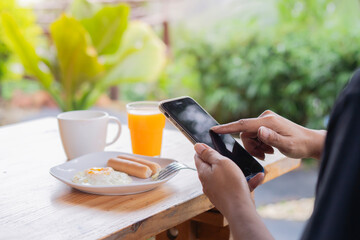 Busineswoman using mobile phone during breakfast at home or hotel.