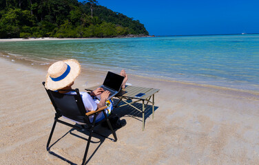 Nomad digital with laptop and running remotely with bright scenic view near poolside on the beach in summer time