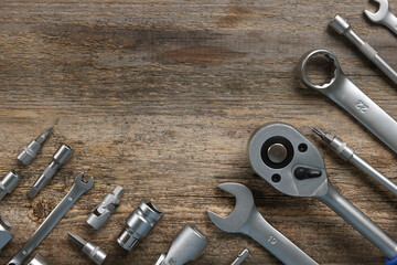 Different auto mechanic's tools on wooden table, flat lay. Space for text