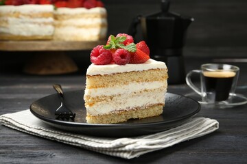 Piece of tasty sponge cake with fresh berries and mint served on black wooden table