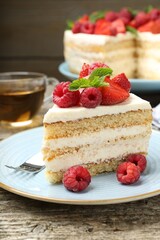 Piece of tasty sponge cake with fresh berries and mint served on wooden table, closeup
