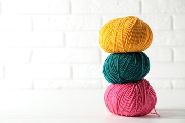 Different colorful yarns on white wooden table, closeup. Space for text