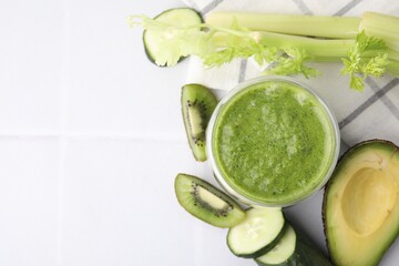 Delicious green smoothie and ingredients on white table, top view. Space for text