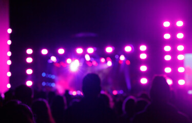 Silhouettes of spectators against a background of blue and pink light at a concert