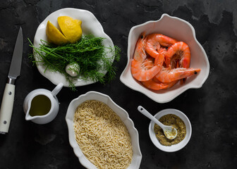 Ingredients for making orzo pasta with shrimp in dill-mustard-lemon marinade on a dark surface
