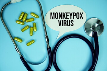 Monkeypox text with stethoscope and capsule medicine on blue background, Healthy and wellness concept