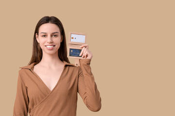 Naklejka premium Young woman with credit card holder on brown background