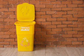 Empty trash bin with PAPER sign near wall. Recycling concept