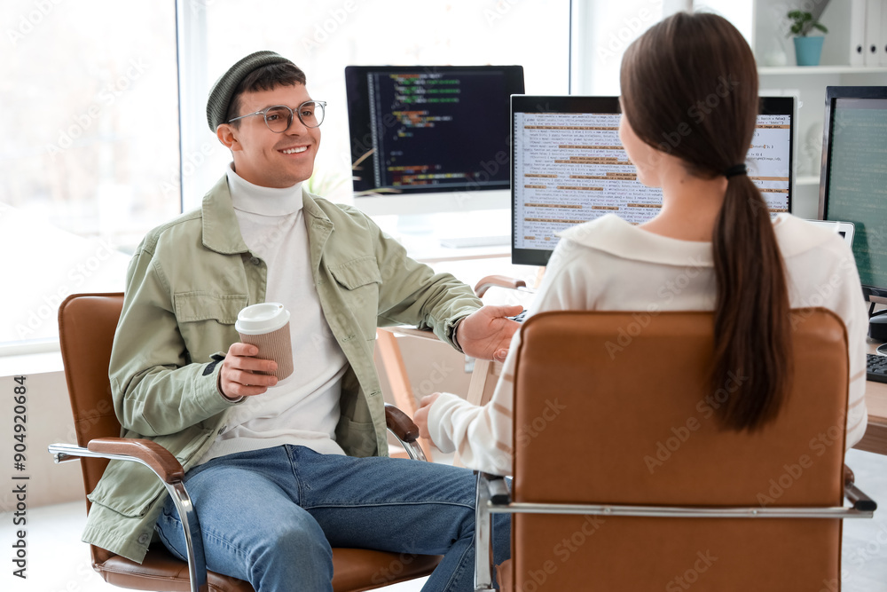 Poster couple of programmers with coffee working at table in office