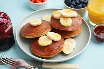 Tasty pancakes with honey and banana on blue background