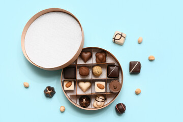 Box with delicious chocolate candies and nuts on blue background