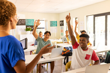 In high school, students raising hands and engaging with teacher in classroom