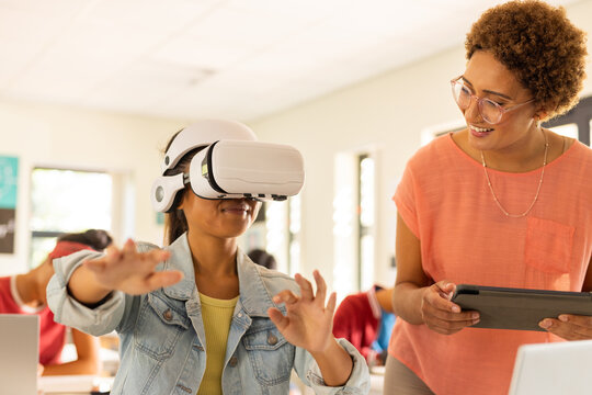 In high school, student using VR headset while teacher with tablet watching - Powered by Adobe