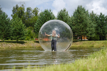Aqua zorbing on water. A girl in a transparent balloon on the water, lake, nature, forest. Girl...