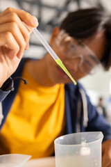 In high school, teenager using pipette for science experiment in classroom