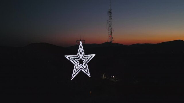 Downward aerial pan of Mill Mountain in Roanoke Virginia at warm orange sunset.