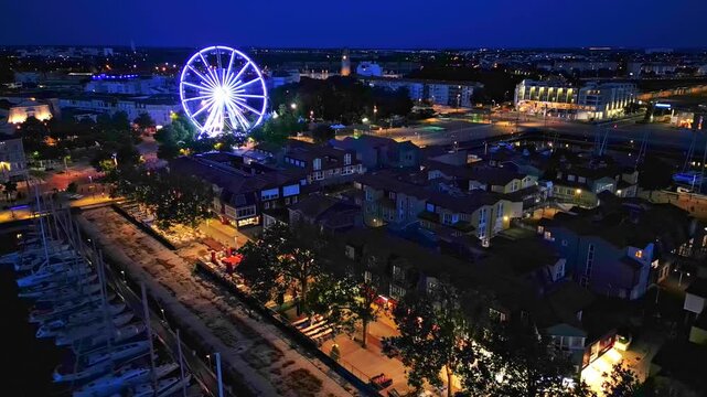 The old port near Quai Valin with big wheel at night, La Rochelle, France. Aerial drone sideways