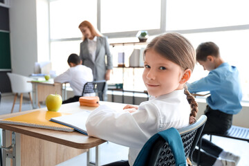 Obraz premium Little schoolgirl having lesson in classroom, closeup