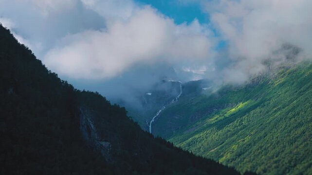 Aerial view of the wide green valley. White fluffy clouds float above and cast dark shadows on the landscape. Hyperlapse. High quality 4k footage