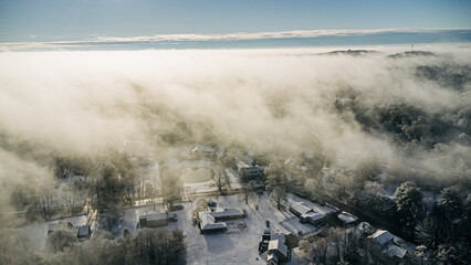 Aerial view of a snowy, fog-covered neighborhood in winter