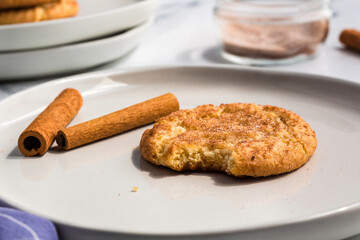 A snickerdoodle cookie  on a plate with cinnamon sticks