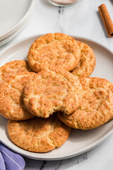A plate of snickerdoodle cookies stacked on a marble countertop.