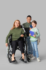 Fototapeta premium Mature teacher in wheelchair with little pupils on light background
