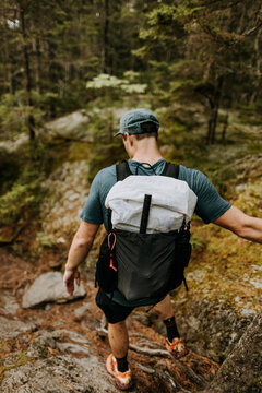 Hiker wearing white backpack navigates Appalachian Trail, Maine