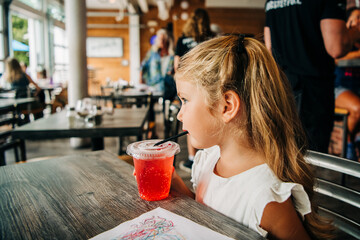 Young girl sipping a drink in a casual restaurant setting