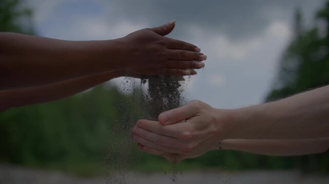 Hands pass sand in a forest symbolizing unity, collaboration, and harmony with the environment