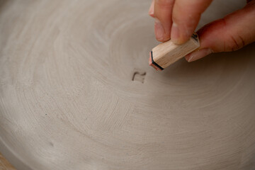 Decorating clay products with special patters and symbols on a ceramics workshop. Using a clay...
