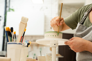 Girl is making a colorful decoration of a clay project with paint and water. Painting ceramic...