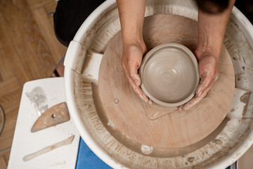Creating a ceramic bowl by yourself in a pottery class. Wheel throwing. Learning how to model clay into different shapes with pottery wheel.