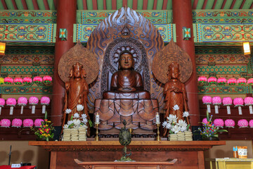 Buyeo-gun, Chungcheongnam-do, South Korea - August 12, 2022: Interior and front view of tree Buddha statue with a incense burner in Daeungjeon Hall of Neungsa Temple at Sabi Palace
