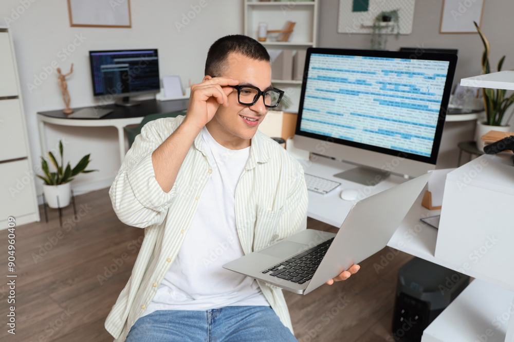 Poster handsome programmer working with laptop in office