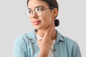 Young woman checking her pulse on light background, closeup
