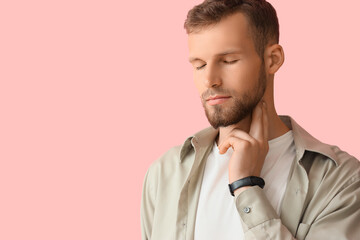 Fototapeta premium Young man checking his pulse on pink background, closeup