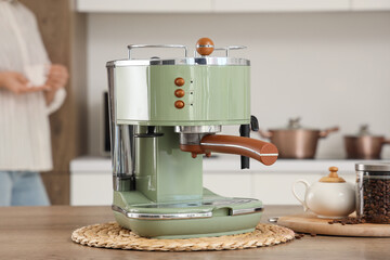 Woman and modern green coffee machine on table in kitchen, closeup
