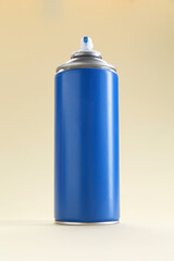 Blue spray paint can on beige background