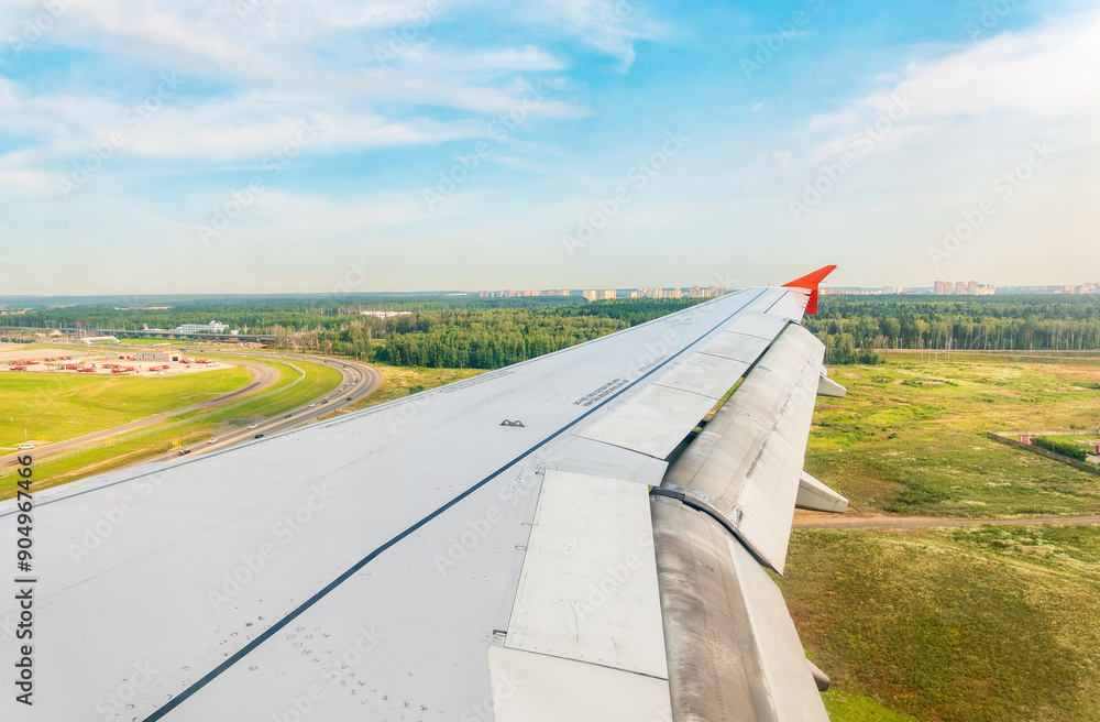 Wall mural view of airplane wing, blue skies and green land during landing. airplane window view.